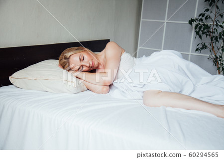 Beautiful blonde woman sleeps in the bedroom on the bed 60294565