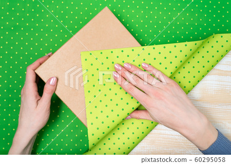 Female hands pack a gift in a green polka-dot 60295058