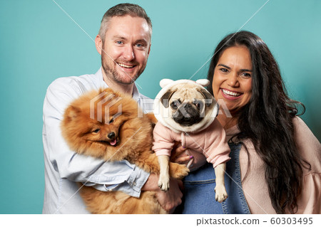 Young pregnant woman and man hold dogs on hands on green background 60303495