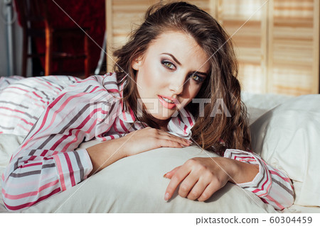 girl in pajamas woke up in the morning is sitting on a bed 60304459