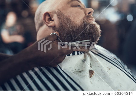 Hairstylist making beard shape using his scissor Hairstylist making beard shape using his scissor 60304514