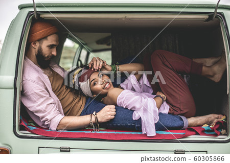 Hippie beloved couple laying in retro van trunk Hippie beloved couple laying in retro van trunk 60305866