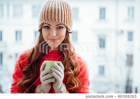 the girl in the hat froze and drinking hot tea 60308263