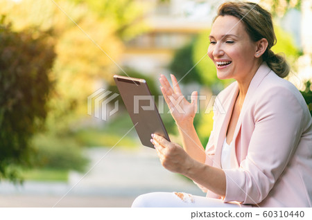 Smiling businesswoman with a tablet in the park. Smiling businesswoman with a tablet in the park. 60310440