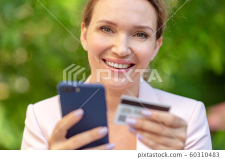 Businesswoman with a credit card and phone makes 60310483