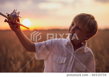 Happy child playing with a toy plane in nature 60310734