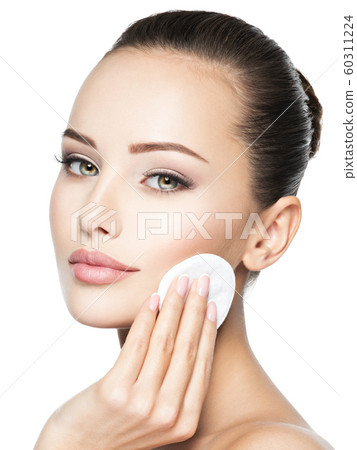 Beautiful woman cleans the face with cotton swab. Beautiful woman cleans the face with cotton swab. 60311224