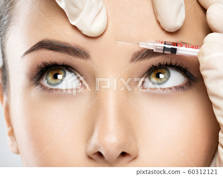 woman getting cosmetic botox injection in forehead 60312121