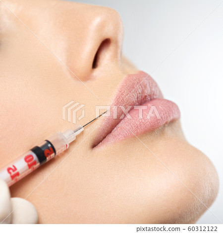 young woman gets botox injection in her lips 60312122