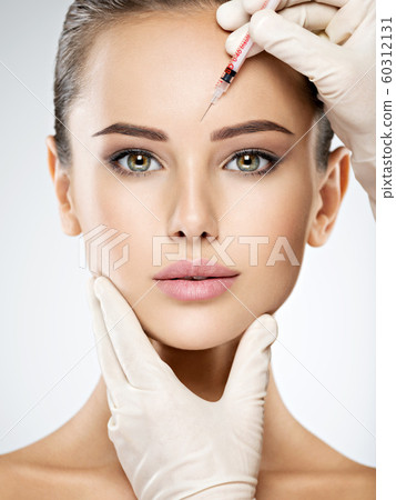 woman getting cosmetic botox injection in forehead 60312131