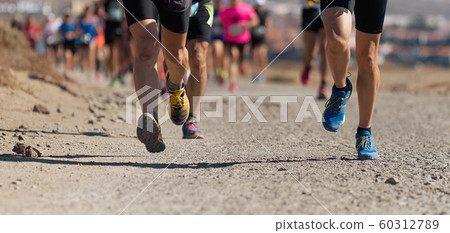 Runners running shoes on trail run. Ultra running athletes legs close up on running in rock path trail Runners running shoes on trail run. Ultra running athletes legs close up on running in rock path trail 60312789