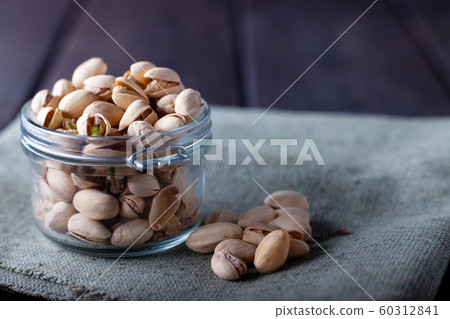 Pistachios in glass jars on a wooden background 60312841