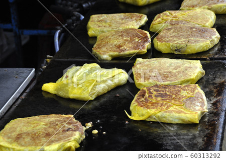 Malaysian street food called Murtabak. Cook by Hawkers. In it there is a mixture of meat, eggs and onions. Eaten with a special gravy. 60313292