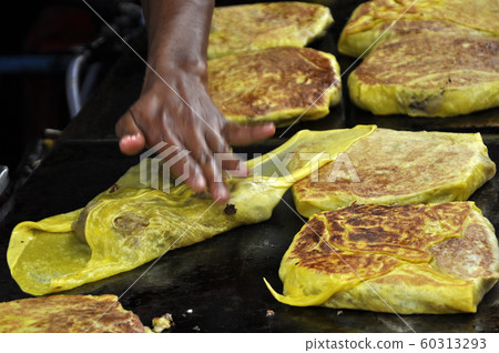 Malaysian street food called Murtabak. Cook by Hawkers. In it there is a mixture of meat, eggs and onions. Eaten with a special gravy. 60313293
