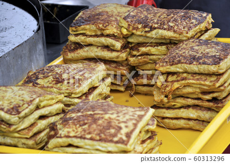 Malaysian street food called Murtabak. Cook by Hawkers. In it there is a mixture of meat, eggs and onions. Eaten with a special gravy. 60313296