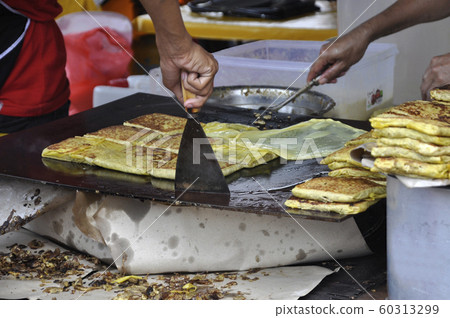 Malaysian street food called Murtabak. Cook by Hawkers. In it there is a mixture of meat, eggs and onions. Eaten with a special gravy. 60313299