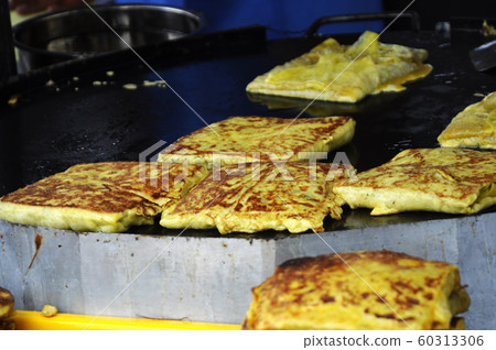 Malaysian street food called Murtabak. Cook by Hawkers. In it there is a mixture of meat, eggs and onions. Eaten with a special gravy. 60313306