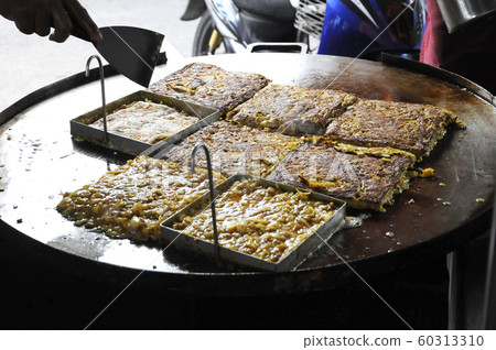 Malaysian street food called Murtabak. Cook by Hawkers. In it there is a mixture of meat, eggs and onions. Eaten with a special gravy. 60313310