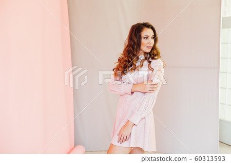Portrait of a beautiful fashionable woman with hair curls in a pink dress 60313593