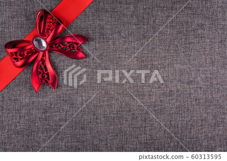Red metal bow and red satin ribbon on gray burlap 60313595