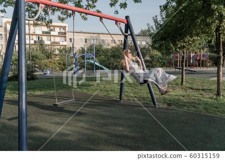 woman rides on a children swing woman rides on a children swing 60315159