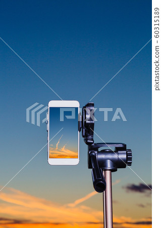 Smartphone on tripod capturing image of sundown in vertical mode Smartphone on tripod capturing image of sundown in vertical mode 60315189