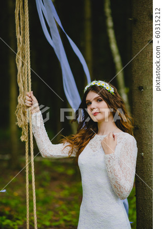 Beautiful young bride posing near the rope swing 60315212