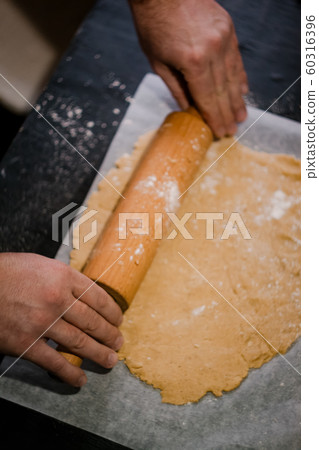 baker's hands roll ginger dough on a dark 60316396