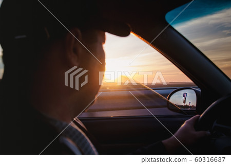 man driving a car at sunset-dawn, close-up, blur. 60316687