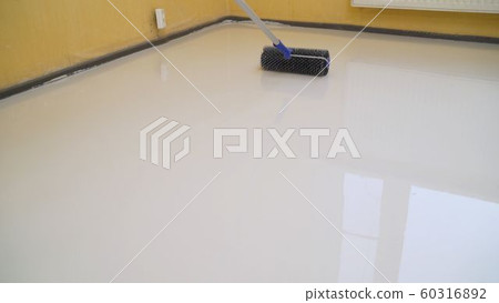Worker rolls liquid floor. Needle roller for bulk floors. A worker fills the floor with a needle roller for bulk floors. Finishing work - the worker is filling the floor. 60316892