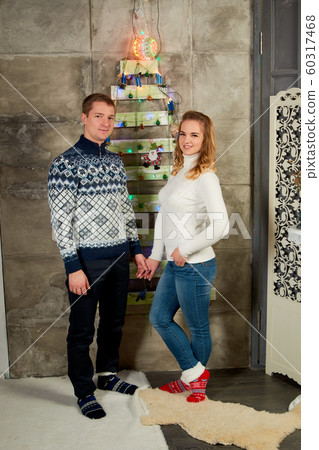 Beautiful young couple in love have fun on Christmas tree background. New Year party. Portrait of attractive just married couple. Modern family. 60317468