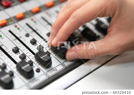 Male hand on control Fader on console. Sound recording studio mixing desk with engineer or music 60320410