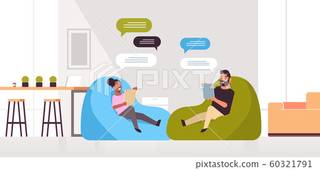 man woman chatting messaging mix race couple sitting at bean bag using mobile app on tablet social network chat bubble communication concept modern living room interior full length horizontal 60321791