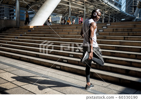 Black man stretch legs and listen music 60330190