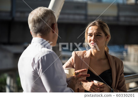Old boss and business woman talk and drink coffee 60330201