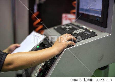 Factory worker on keyboard to command machine Factory worker on keyboard to command machine 60330205