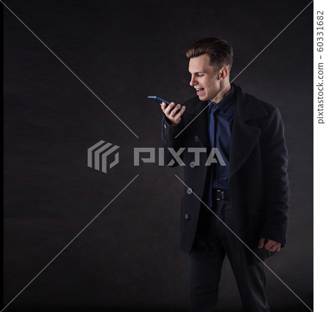 A handsome man in a coat screams while talking on the phone. A handsome man in a coat screams while talking on the phone. 60331682