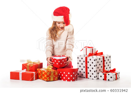 Cute girl in santa claus hat opens christmas presents Cute girl in santa claus hat opens christmas presents 60331942