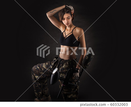 pretty woman in equipment with a paintball gun on a black background. pretty woman in equipment with a paintball gun on a black background. 60332003