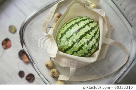 Organic watermelon in eco friendly cotton bag on chair Organic watermelon in eco friendly cotton bag on chair 60333310
