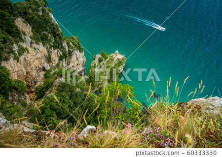 Lighthouse on sheer coast with boat and bright sea 60333330