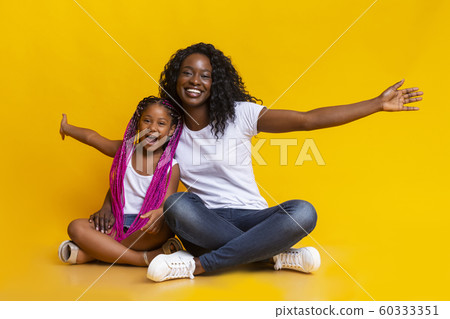 Little afro girl sitting with mom and repeating her gestures 60333351