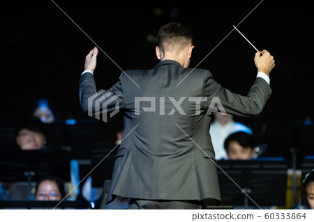 Male band conductor conducting his concert band Male band conductor conducting his concert band 60333864