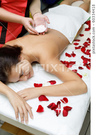Masseur applying cream to woman's back 60334418