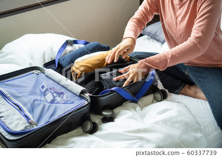 Happy young woman hands packing clothes into 60337739