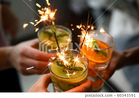 Young group friends hold in hand cocktail with sparkler 60343591