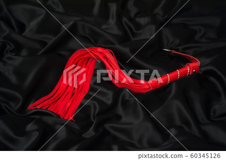 Red whip on a black silk background. Accessories 60345126
