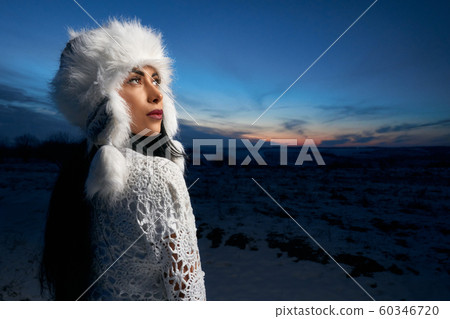 Girl in white warm hat on field covered with snow. 60346720
