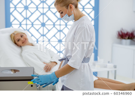 Masked female beautician is standing near centrifuge 60346960