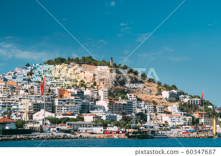 Kusadasi, Aydin Province, Turkey. Waterfront And Kusadasi Cityscape In Sunny Summer Day. Scenic View Of Kusadasi Skyline At Aegean Coast, Turkey Kusadasi, Aydin Province, Turkey. Waterfront And Kusadasi Cityscape In Sunny Summer Day. Scenic View Of Kusadasi Skyline At Aegean Coast, Turkey 60347687